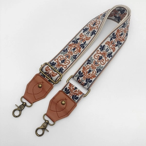 Detail of colorful ethnic embroidery strap with bronze metal hooks and leather ends