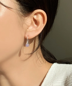 Close-up of a model wearing a purple spherical agate drop earring in 925 sterling silver