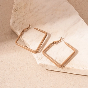 Detail view of square beige lacquer geometric earrings on a natural light stone base