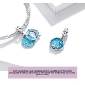Macro shot of S925 silver ocean dolphin charm with blue glitter enamel and waves