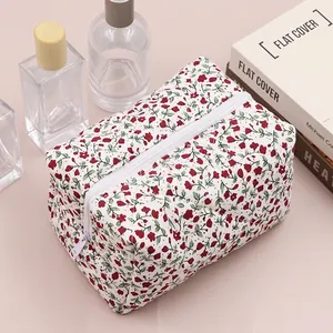 Close-up of floral quilted cotton makeup bag with red flowers and white zipper detail