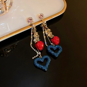 Detail view of rhinestone strawberry heart and tassel earrings with sparkling star accents