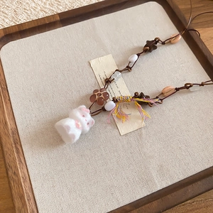 Detail of handmade bunny plush pendant with colorful beads and flower accents on long cord