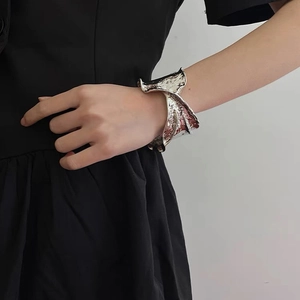 Close-up of wide silver cuff bracelet with irregular hammered texture on model wrist