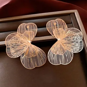 Elegant gold hollow petal earrings with layered mesh design on a brown display box