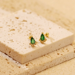 Detail of s925 silver emerald stud earrings on a textured stone background