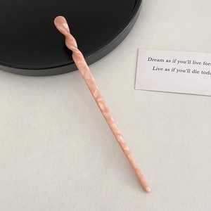 Detail of pink marble pattern hair stick with minimalist spiral twist design