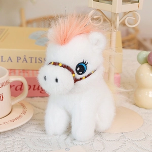 Detail of white plush pony doll with pink mane, blue embroidered eyes and horse harness