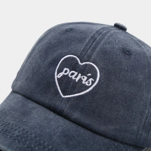 Close-up of white heart embroidery with Paris script on washed cotton baseball cap