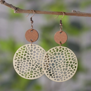 Detail of vintage round wooden earrings with hollow patterns hanging on a branch