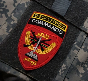 Macro detail of high-density embroidered Special Forces Commando patch on ACU camouflage
