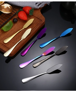Set bunter Buttermesser aus Edelstahl auf Holz und schwarzer Oberfläche präsentiert