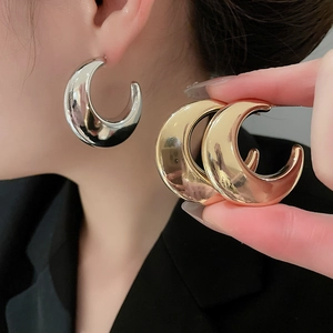 Close-up of polished gold and silver C-shaped drop earrings showing metallic luster