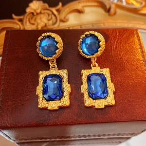 Boucles d'oreilles vintage dorées avec gemmes bleu foncé sur boîte en cuir brun