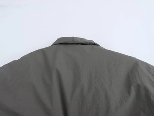 Detailed close-up of dark grey kimono jacket collar and stitching on synthetic fabric