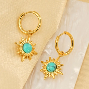 Vintage gold starburst hoop earrings with turquoise stones on elegant silk background