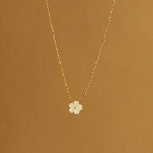 Detail of 18K gold plated necklace featuring a white shell peach blossom pendant