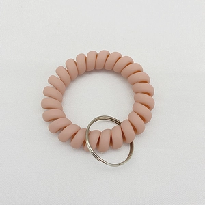 Elastic matte nude pink spiral wrist keychain with silver metal ring on white fabric