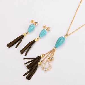 Détail de parure dorée collier et boucles d'oreilles avec turquoise et glands en daim