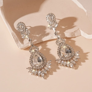 Detailed view of silver drop earrings with floral rhinestones on a beige stone base