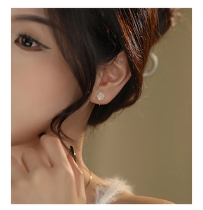 Close-up detail of a minimalist S999 silver rose flower earring worn by a model