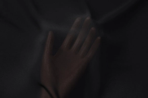 Close-up of black sheer chiffon fabric showing high transparency with hand underneath
