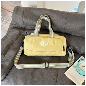 Macro view of light yellow cylinder sports bag with striped green and white handles