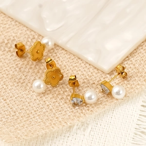 Elegant gold flower pearl studs and geometric zircon earrings set on a textured background