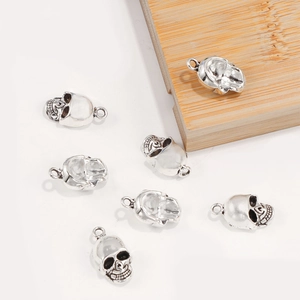 Set of 7 silver alloy skull pendants for DIY jewelry making on white background