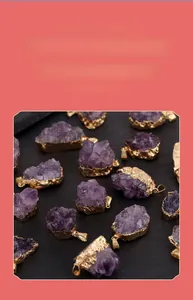 Macro shot of irregular raw amethyst pendant necklaces with gold plated edges on wood