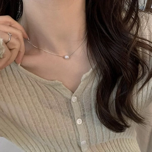 Detail of silver freshwater pearl necklace worn on model for a minimalist chic look