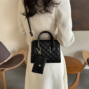 Black quilted crossbody bag with top handles and a matching mini coin purse keychain