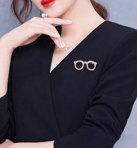 Detailed view of a gold glasses brooch with rhinestones on a black suit lapel