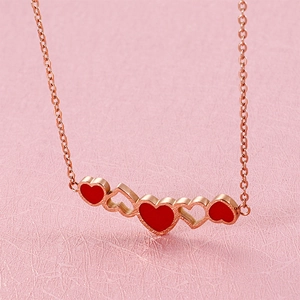 Detail of rose gold necklace with five interlocking red and hollow heart-shaped pendants