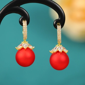 Macro detail of red matte pearl earrings with gold floral diamond setting on black stand