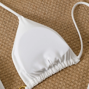 Detail of white triangle bikini top featuring ruched edges and a gold metal ring link