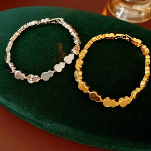Macro shot of gold and silver bear-shaped link bracelets on dark green velvet