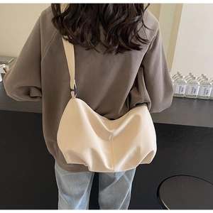 Minimalist beige nylon crescent tote bag shown from the back on a female model
