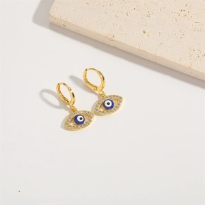 Detail of gold evil eye earrings with blue enamel and sparkling crystal accents