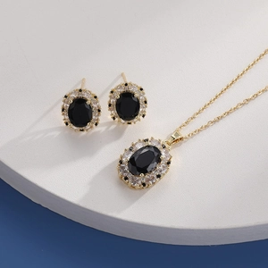 Close-up of gold necklace and earrings set with oval black stones and clear crystals