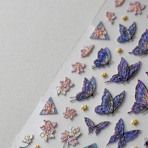 Détail de stickers 3D gaufrés pour ongles avec papillons violets et motifs floraux roses
