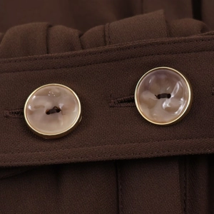 Nahaufnahme von Vintage Marmorknöpfen mit Goldrand auf einem braunen Midikleid Stoff
