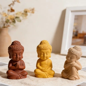 Tre mini statue di Buddha nei colori rosso, giallo e beige con texture di arenaria