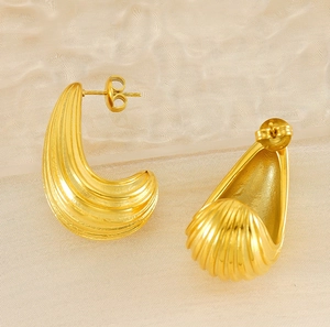 Close-up of gold-plated geometric stud earrings with vertical ridge texture and curved design