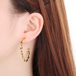 Close-up of twisted gold spiral hoop earrings worn by a model in a minimalist style