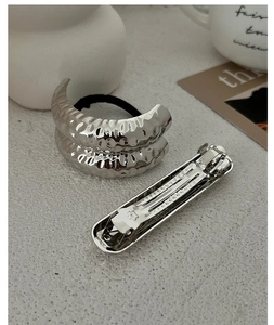 Close-up of silver hammered texture elastic hair tie and spring clip set on table