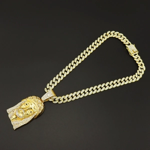 Detailed view of hip hop gold Jesus pendant with sparkling diamonds and Cuban chain