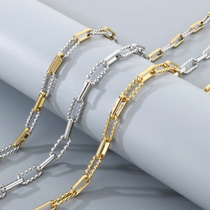 Three-tone Figaro chain necklace set in gold and silver finish on a pedestal