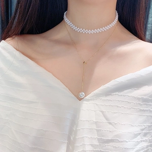 Close-up of double-layer pearl necklace with golden metal chains worn by a model