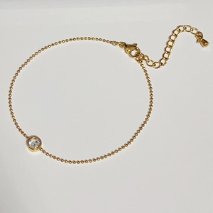 Detail of minimalist 18k gold plated bead chain bracelet with a bezel-set zircon stone